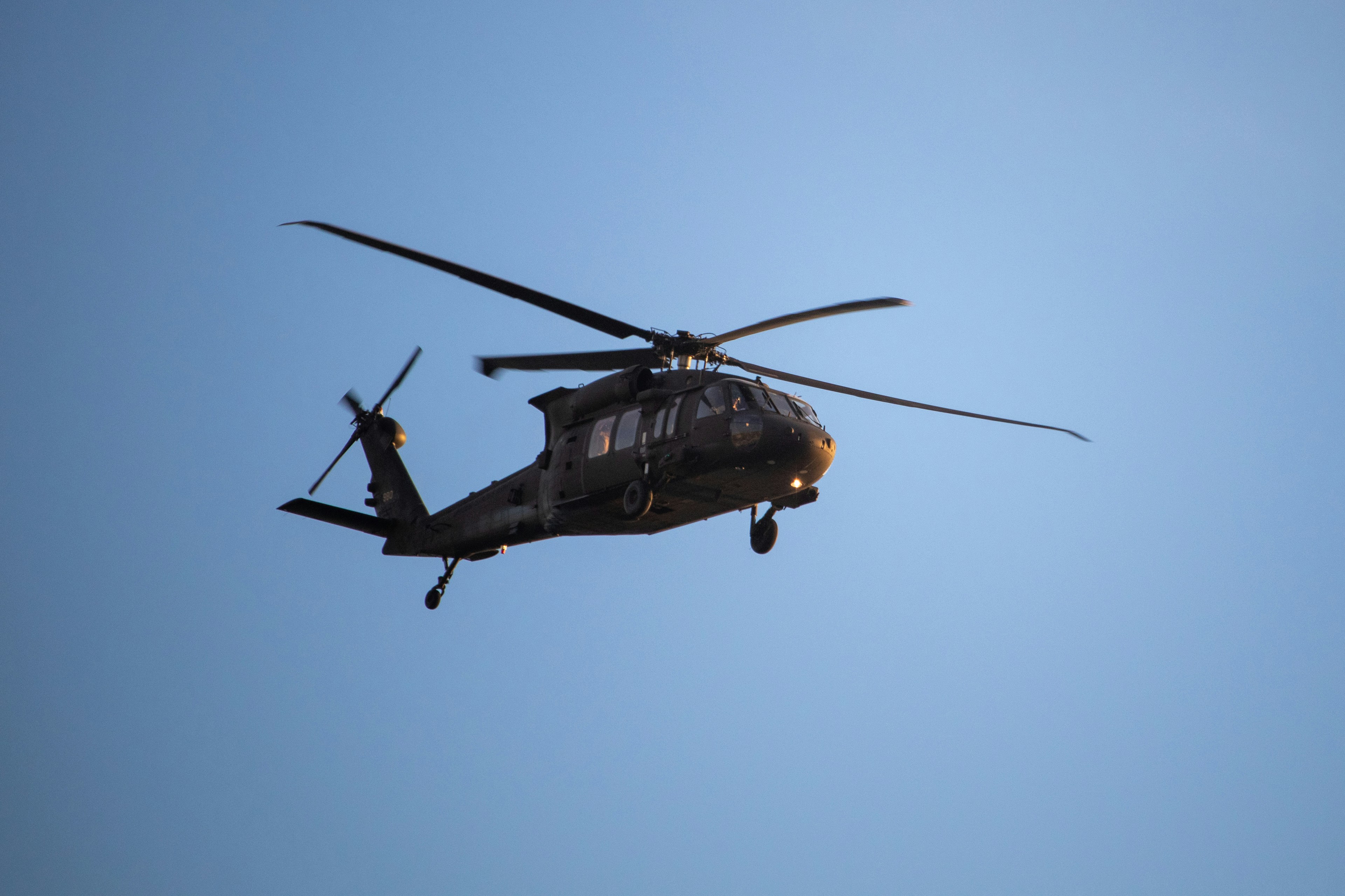 a helicopter flying through a blue sky on a sunny day, Blackhawk helicopter in flight over Laguna Beach, California.