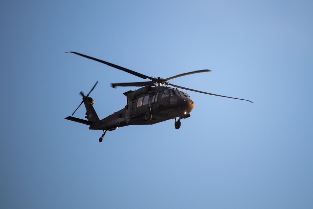 a helicopter flying through a blue sky on a sunny day