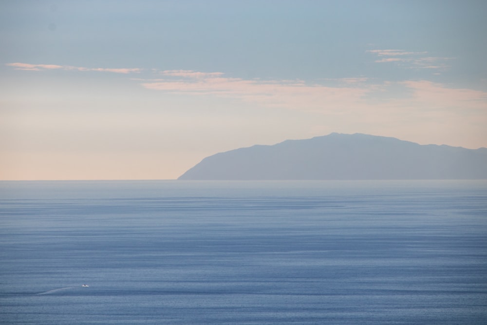 a large body of water with a mountain in the distance