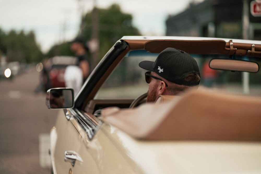 a man driving a convertible car down a street