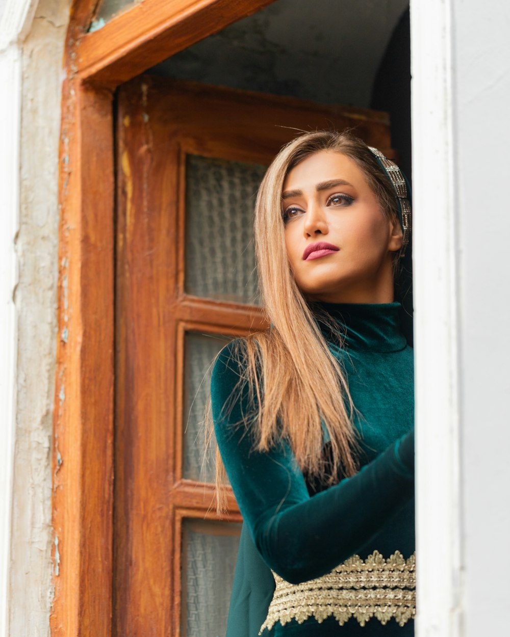 a woman in a green dress looking out of a window