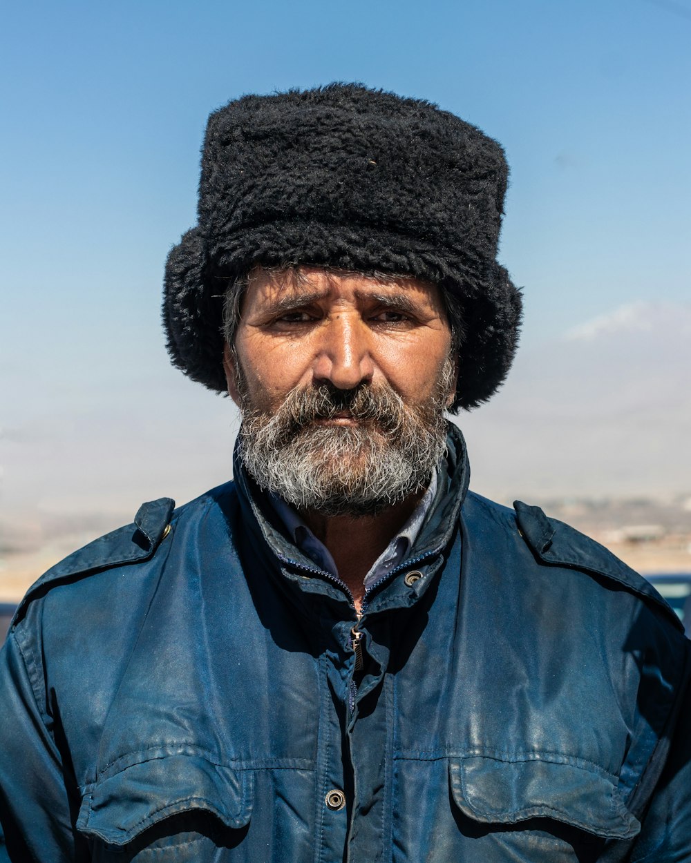 a man with a beard wearing a black hat