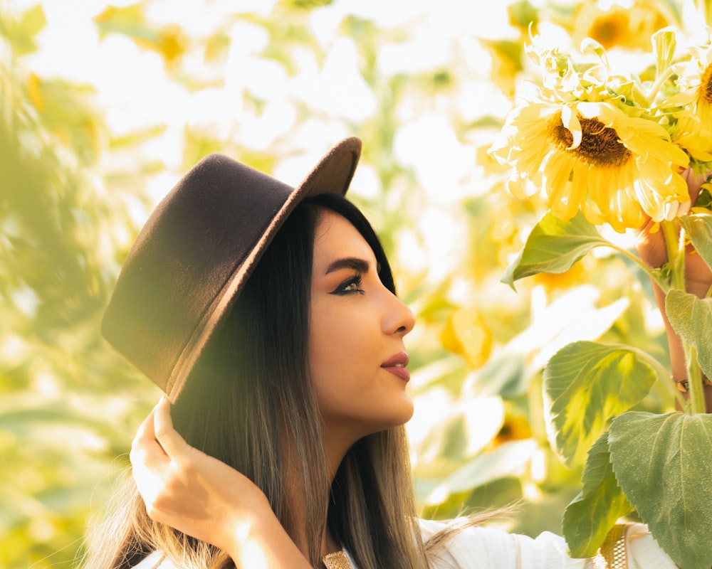 a woman wearing a hat and holding a sunflower