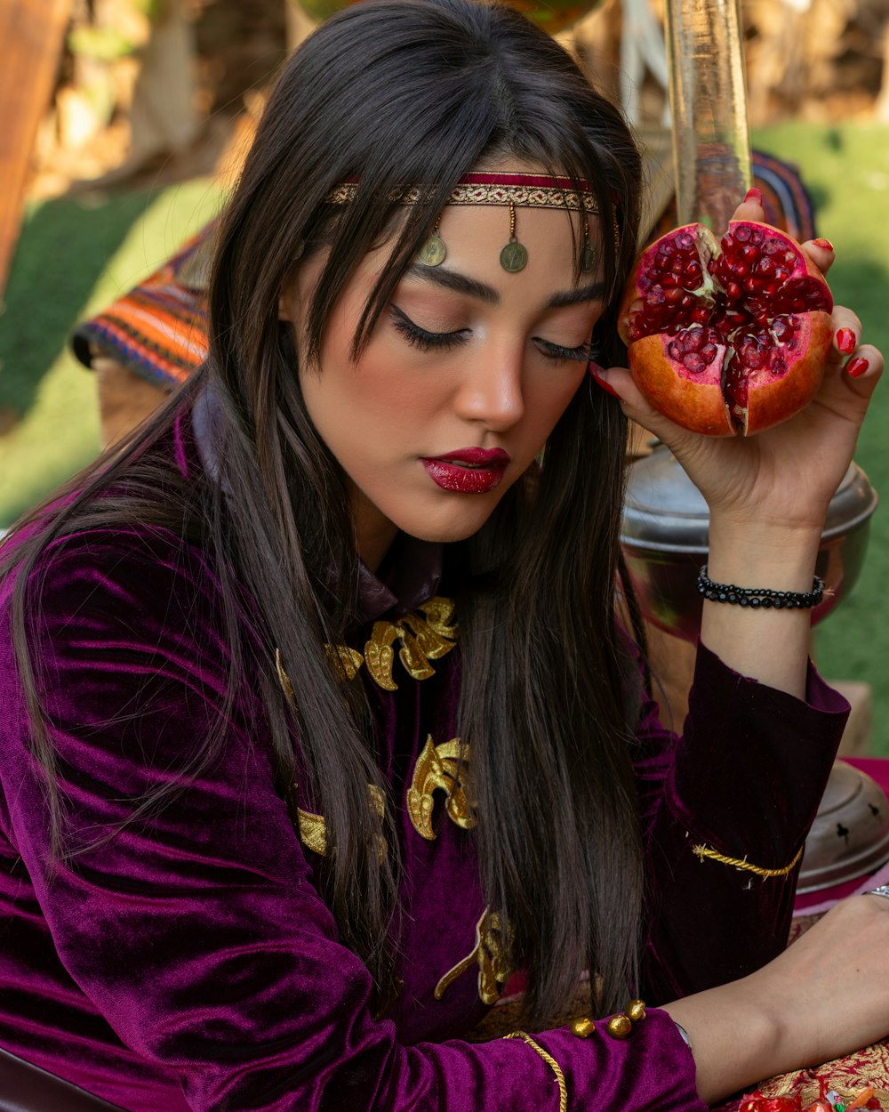 a woman in a purple outfit holding a pomegranate