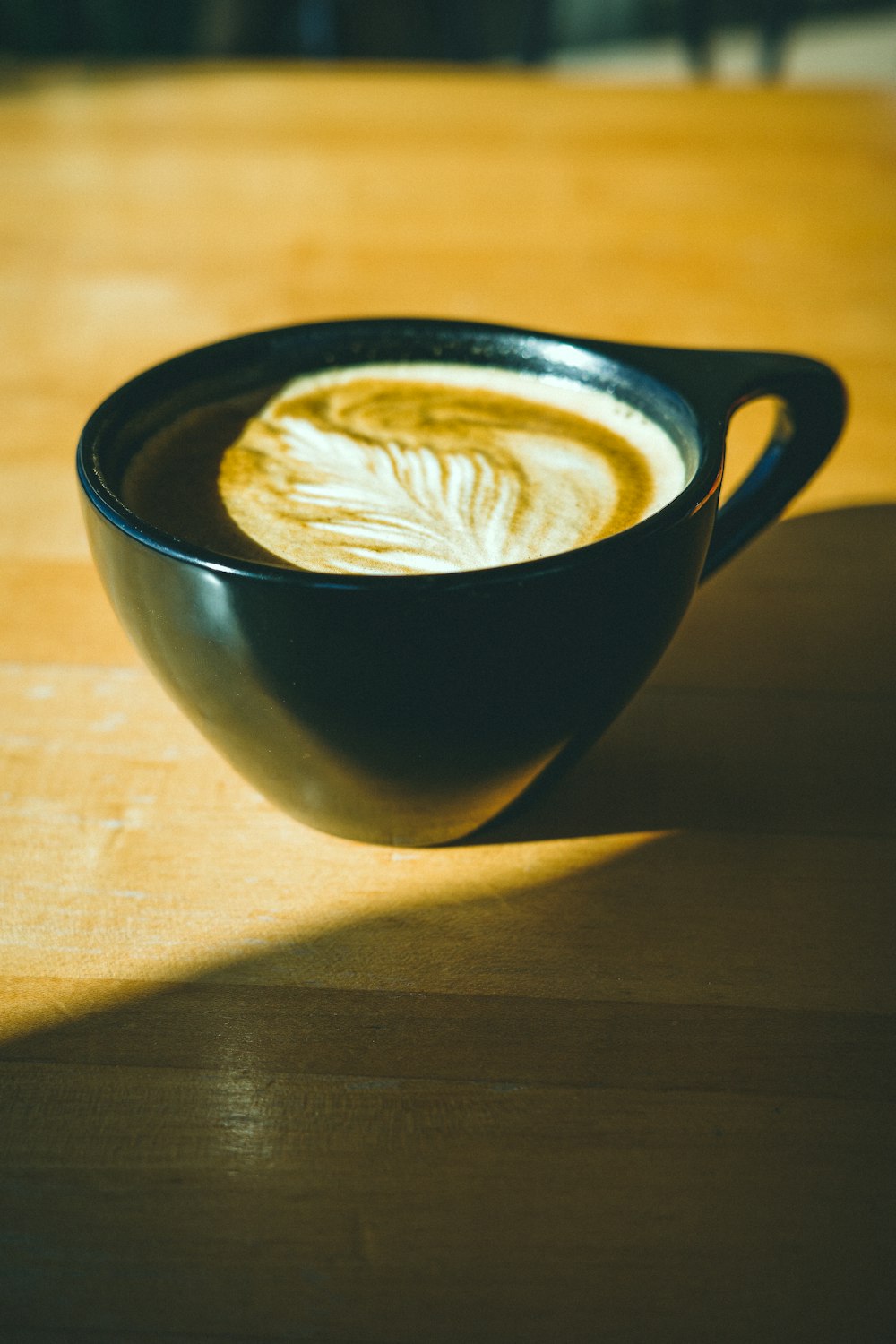 a cup of coffee sitting on top of a wooden table