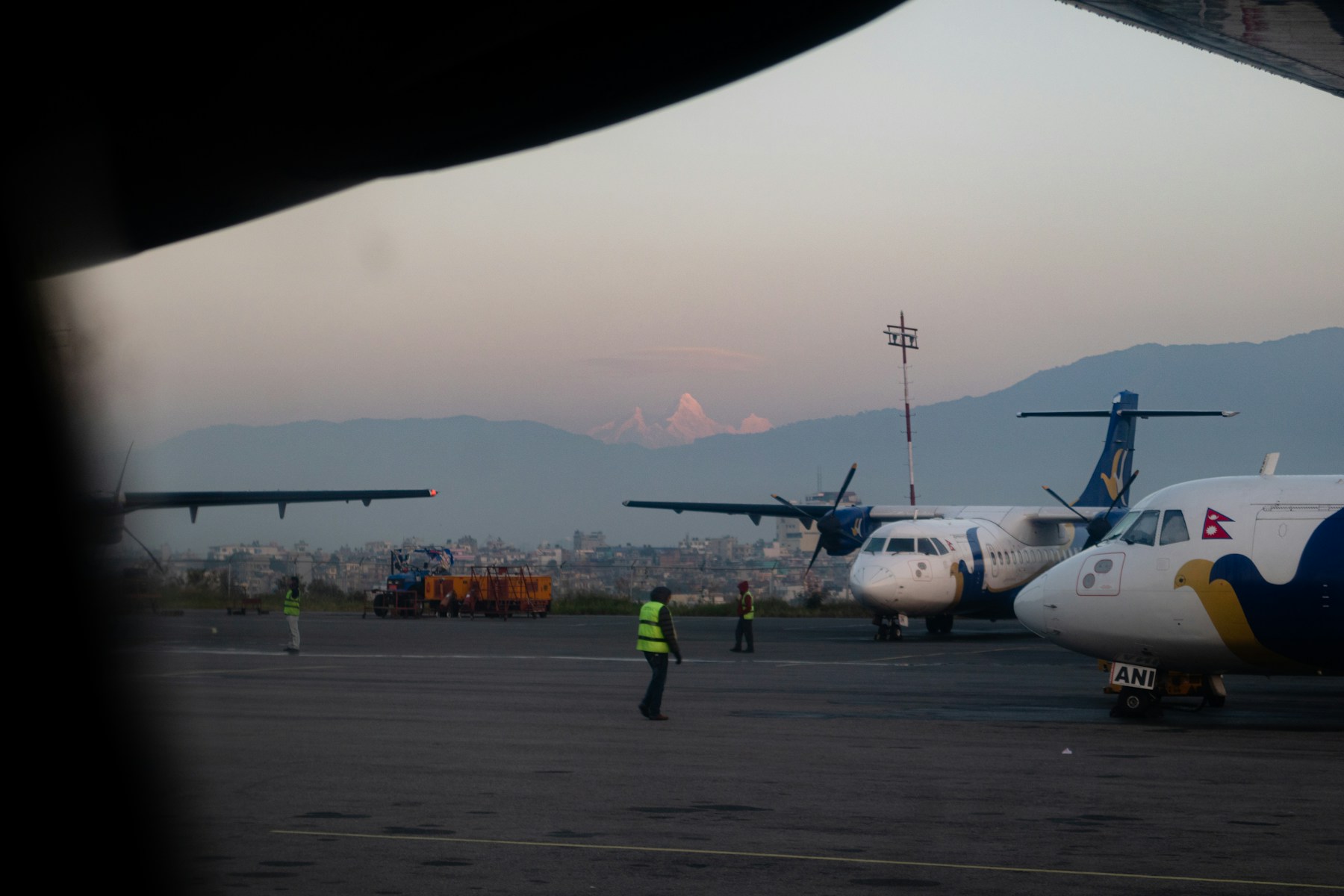 Traveler using smartphone at Kathmandu Airport with mountains in the background