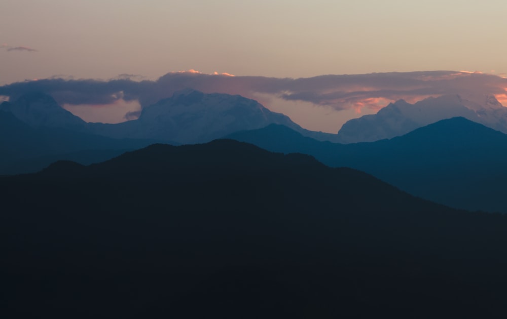 the sun is setting over the mountains in the distance