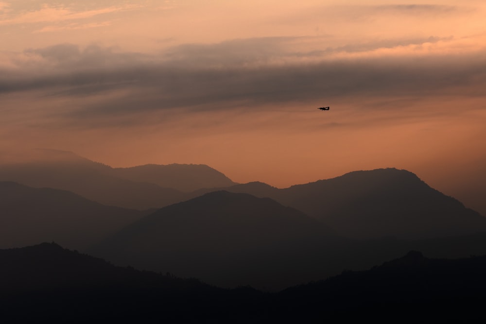 un avión volando sobre una cadena montañosa al atardecer