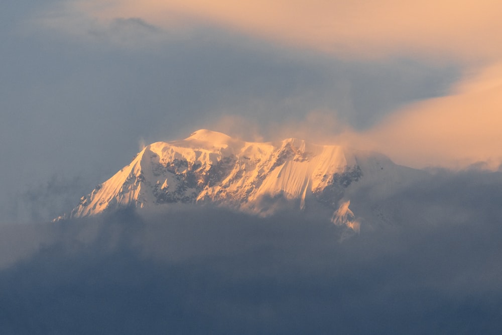 a mountain covered in snow under a cloudy sky