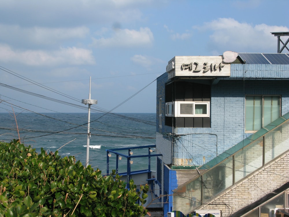 a blue building with the ocean in the background