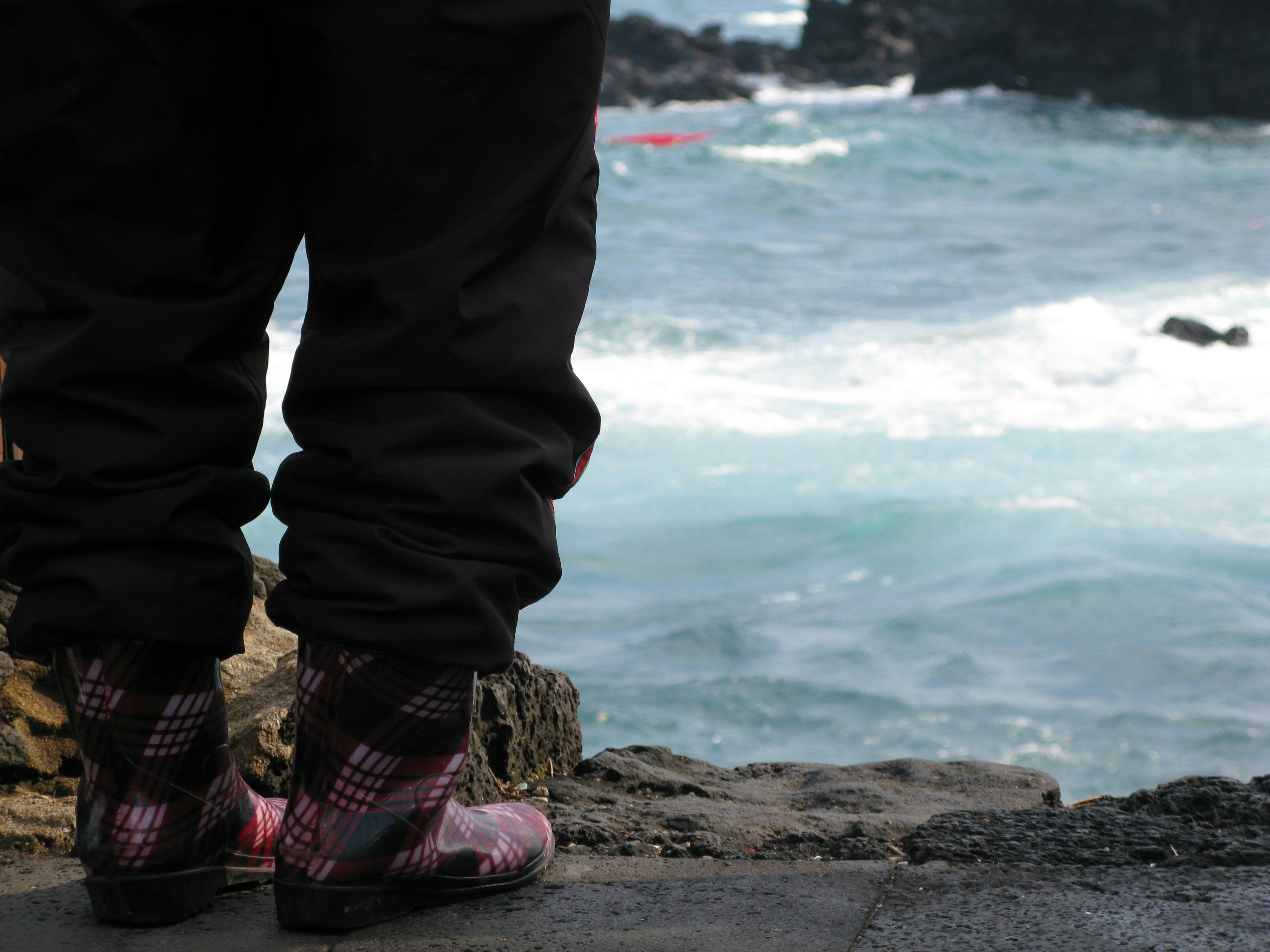 a person standing on a rock next to the ocean