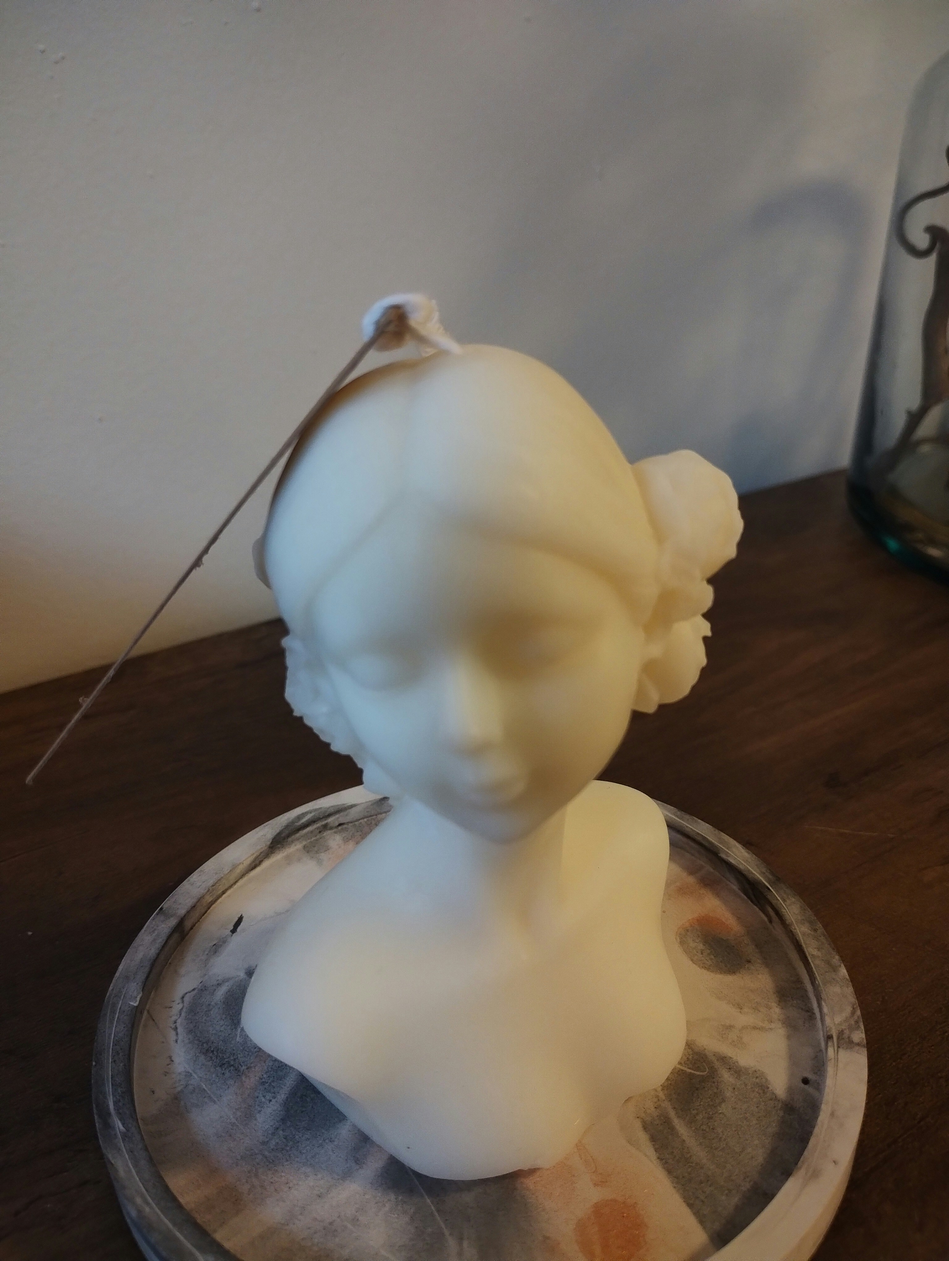 a white sculpture of a woman on a glass plate