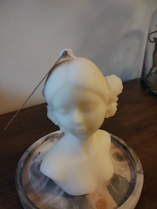 a white sculpture of a woman on a glass plate