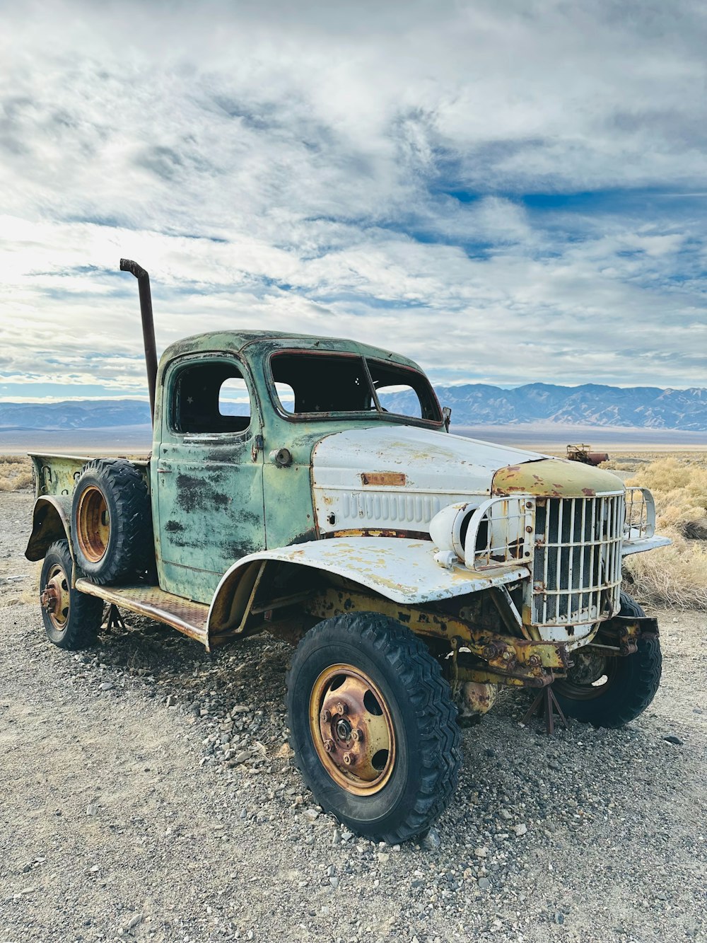 an old truck sitting in the middle of a desert