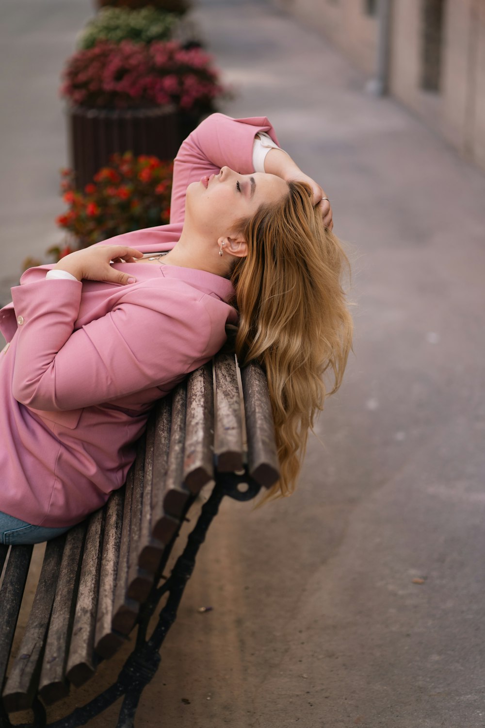 a woman laying on top of a wooden bench