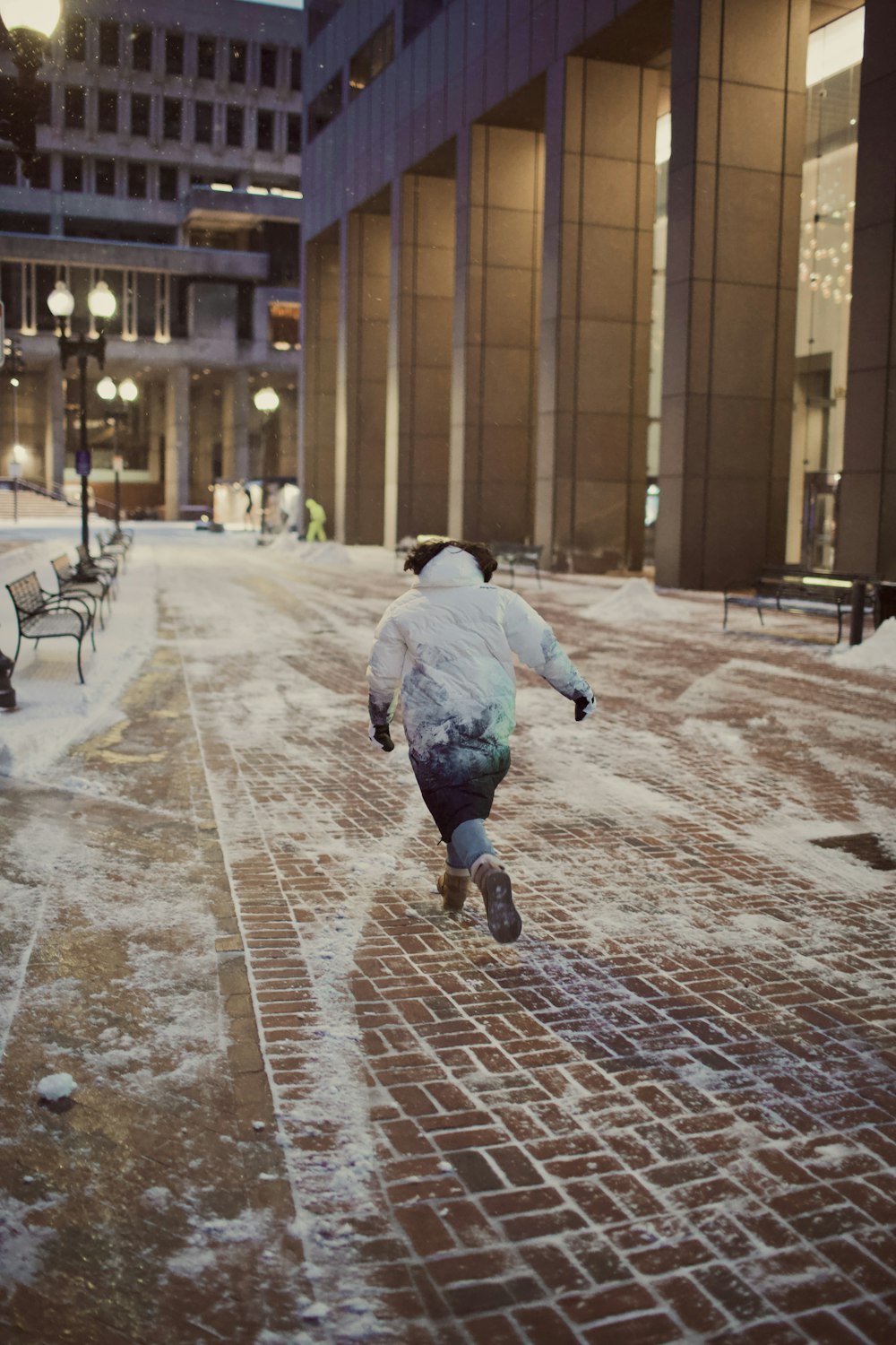 a person riding a skateboard down a snow covered sidewalk