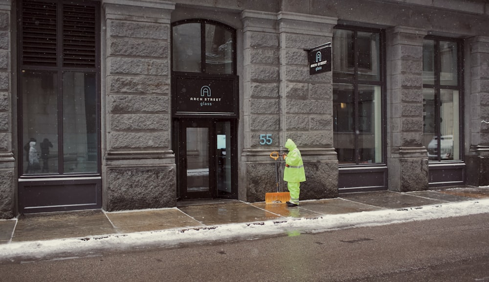 a person in a yellow raincoat standing in front of a building