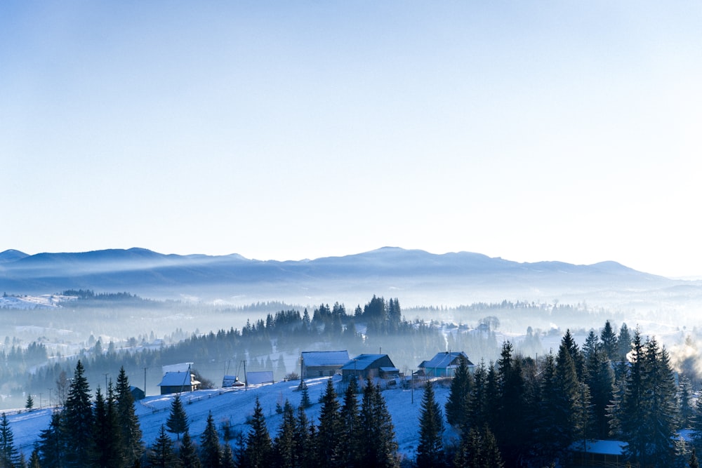 a view of a snowy mountain with houses and trees in the foreground