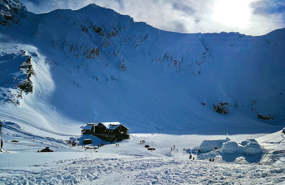 a snow covered mountain with a house on top of it