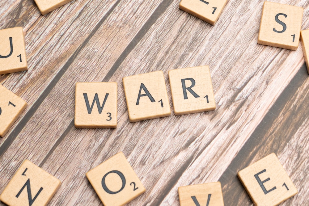 scrabble tiles spelling out the word war on a wooden surface