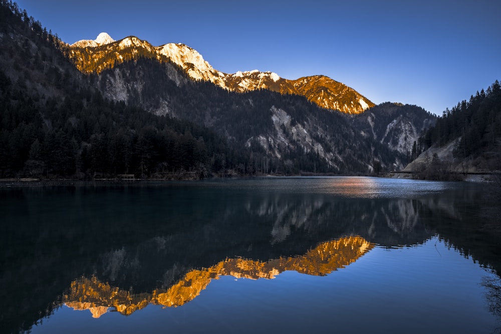 a mountain range is reflected in the still water of a lake