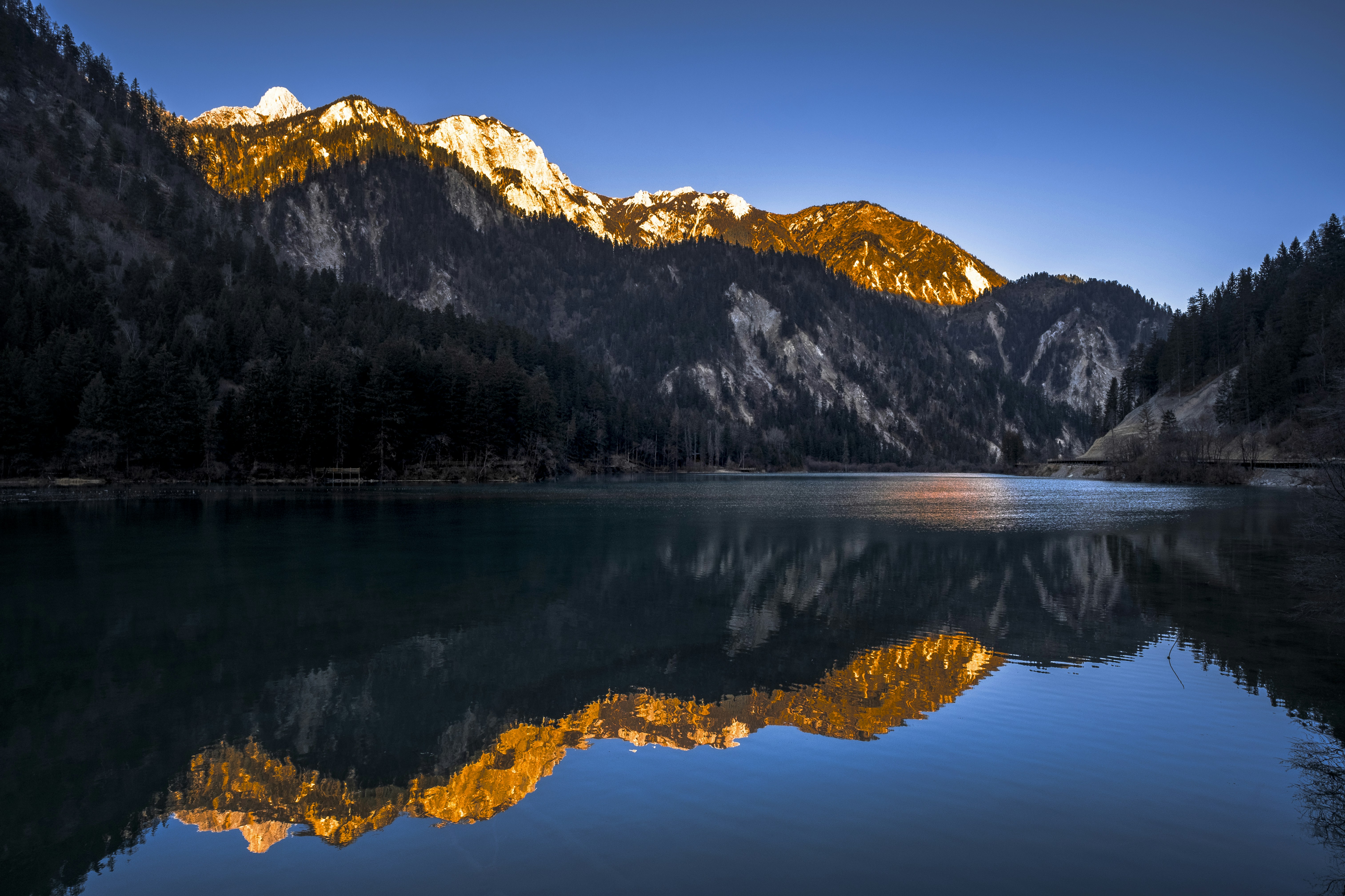a mountain range is reflected in the still water of a lake
