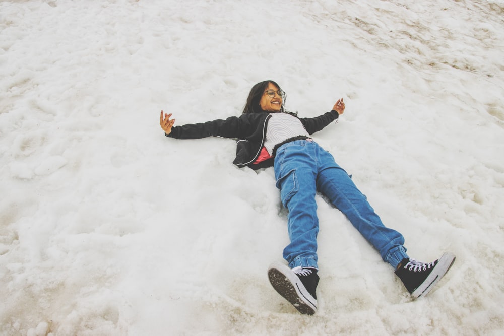 a woman laying in the snow with her arms out