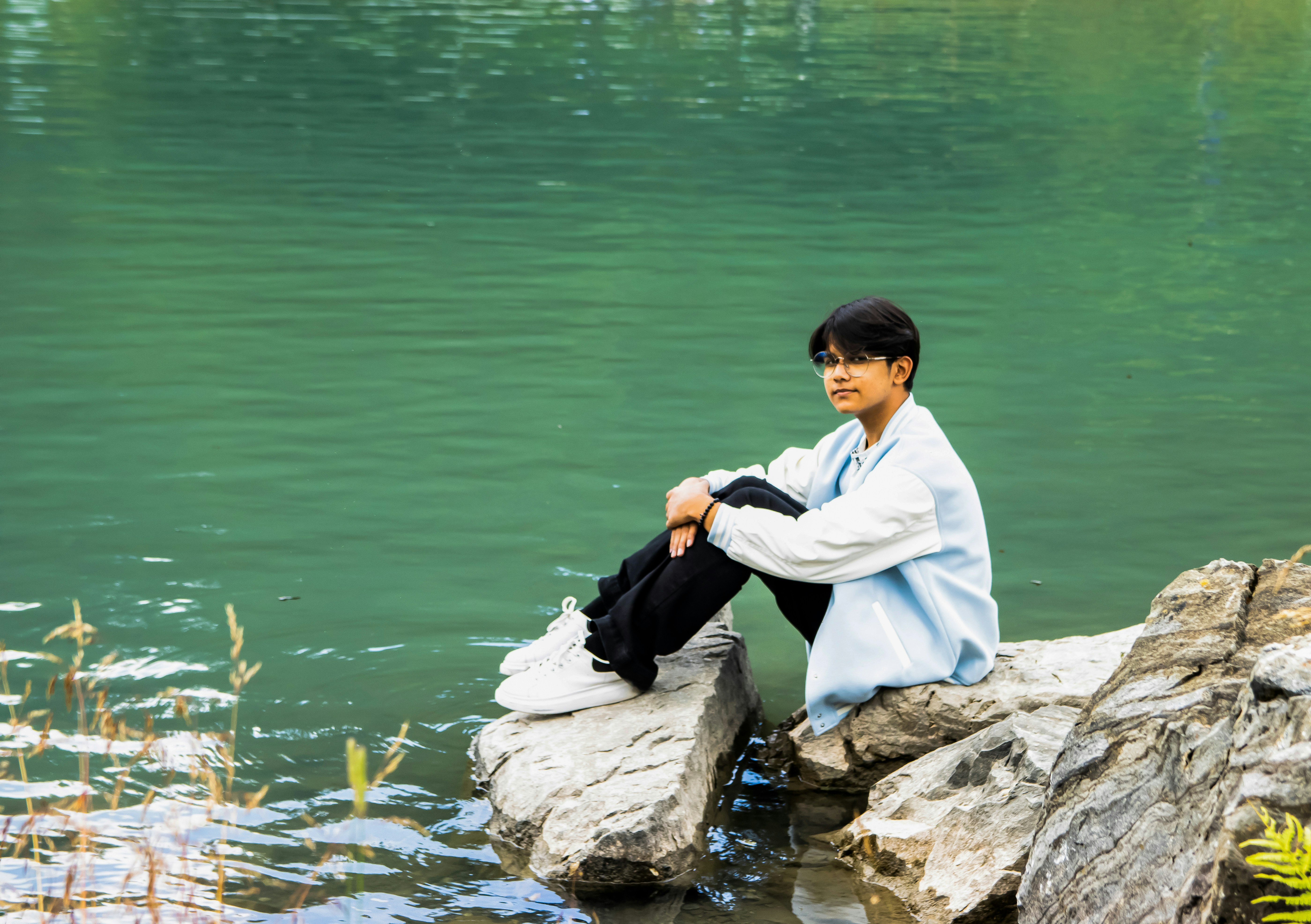 a man sitting on a rock in the water