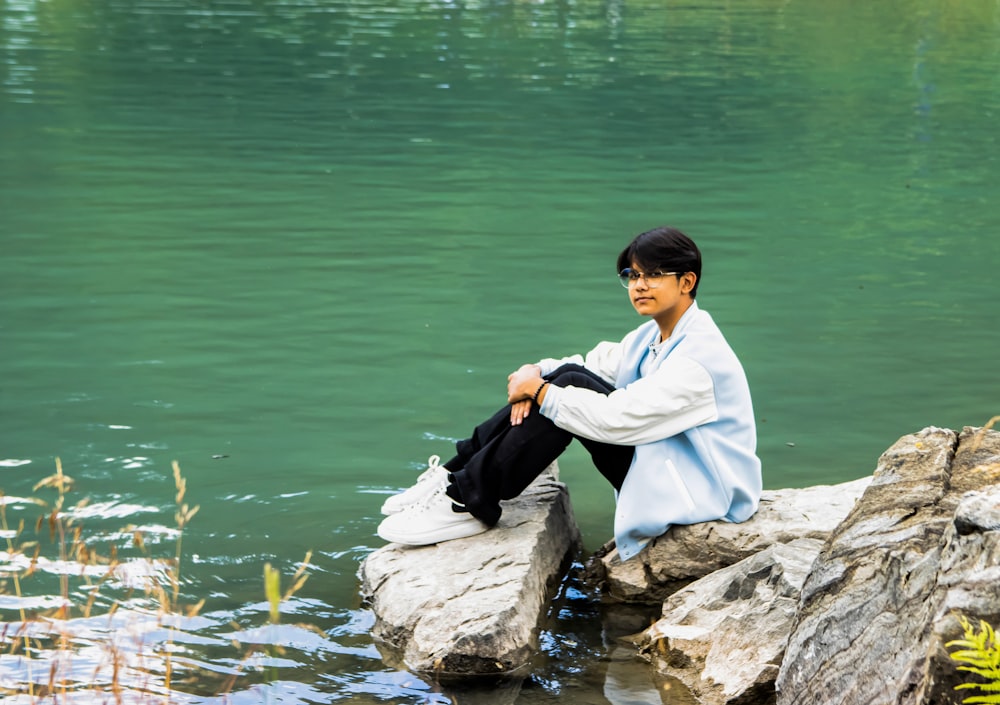 a man sitting on a rock in the water