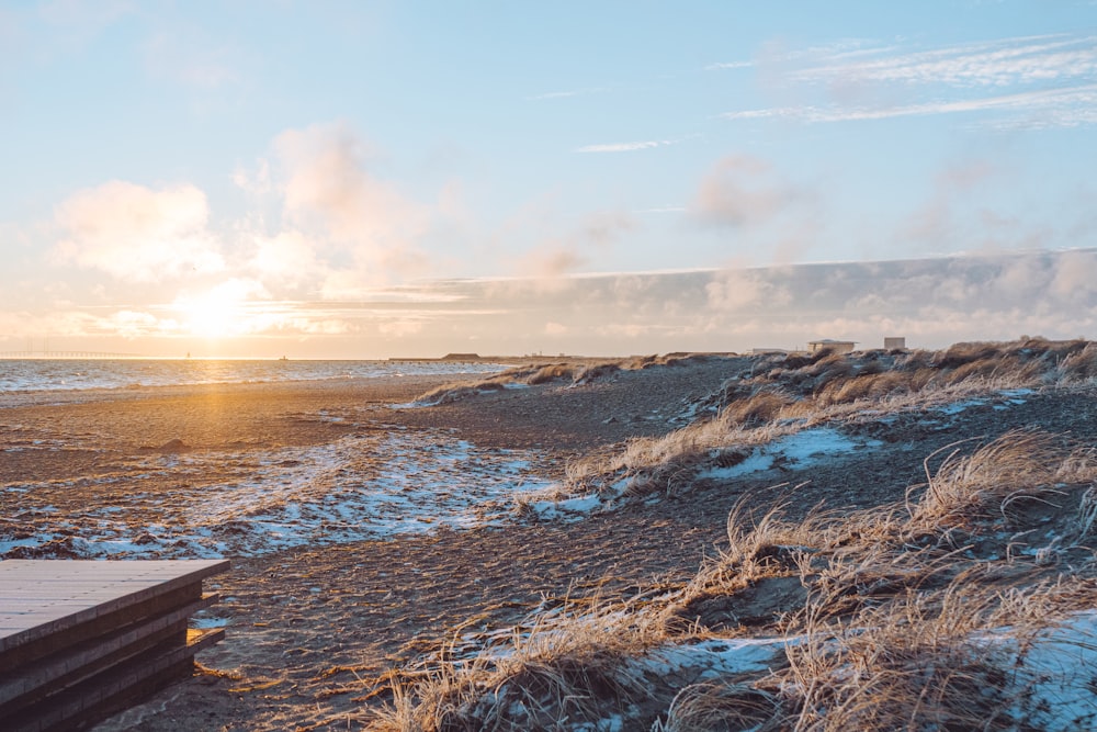 the sun is setting over the beach and the water