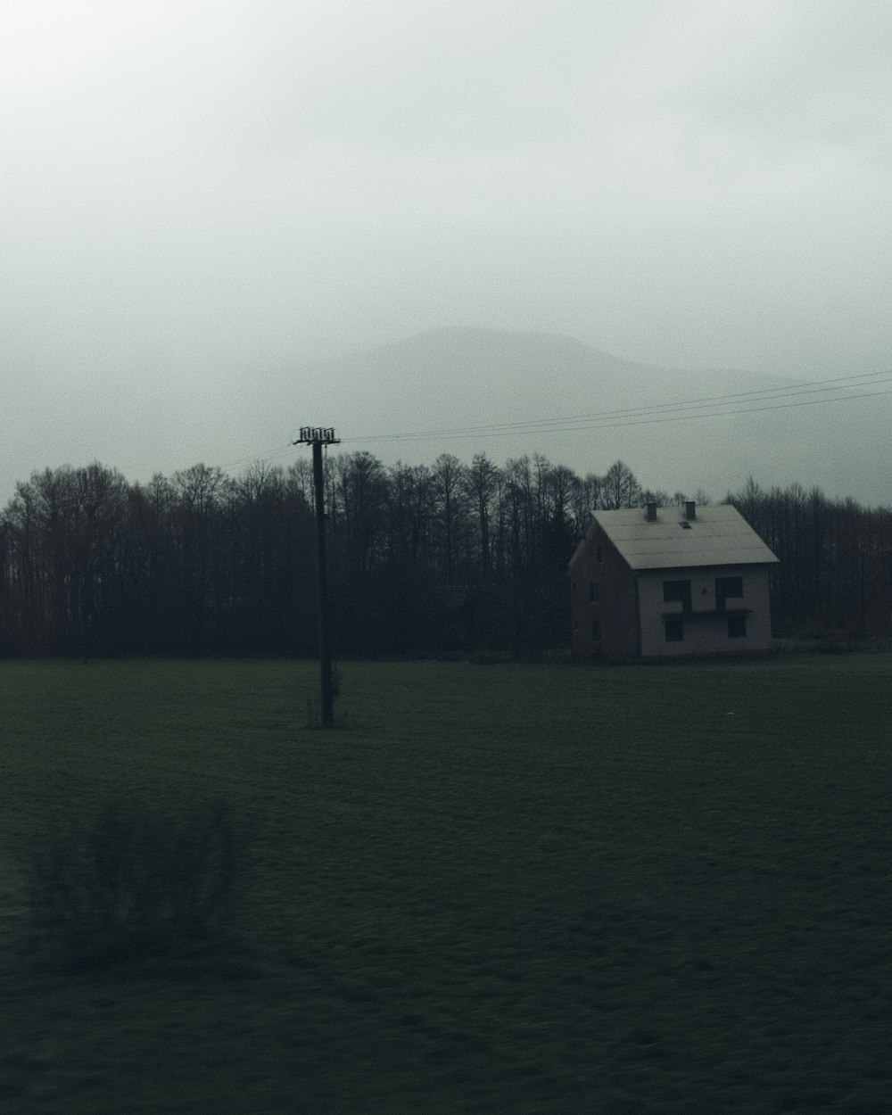 a house in a field with a telephone pole in the foreground