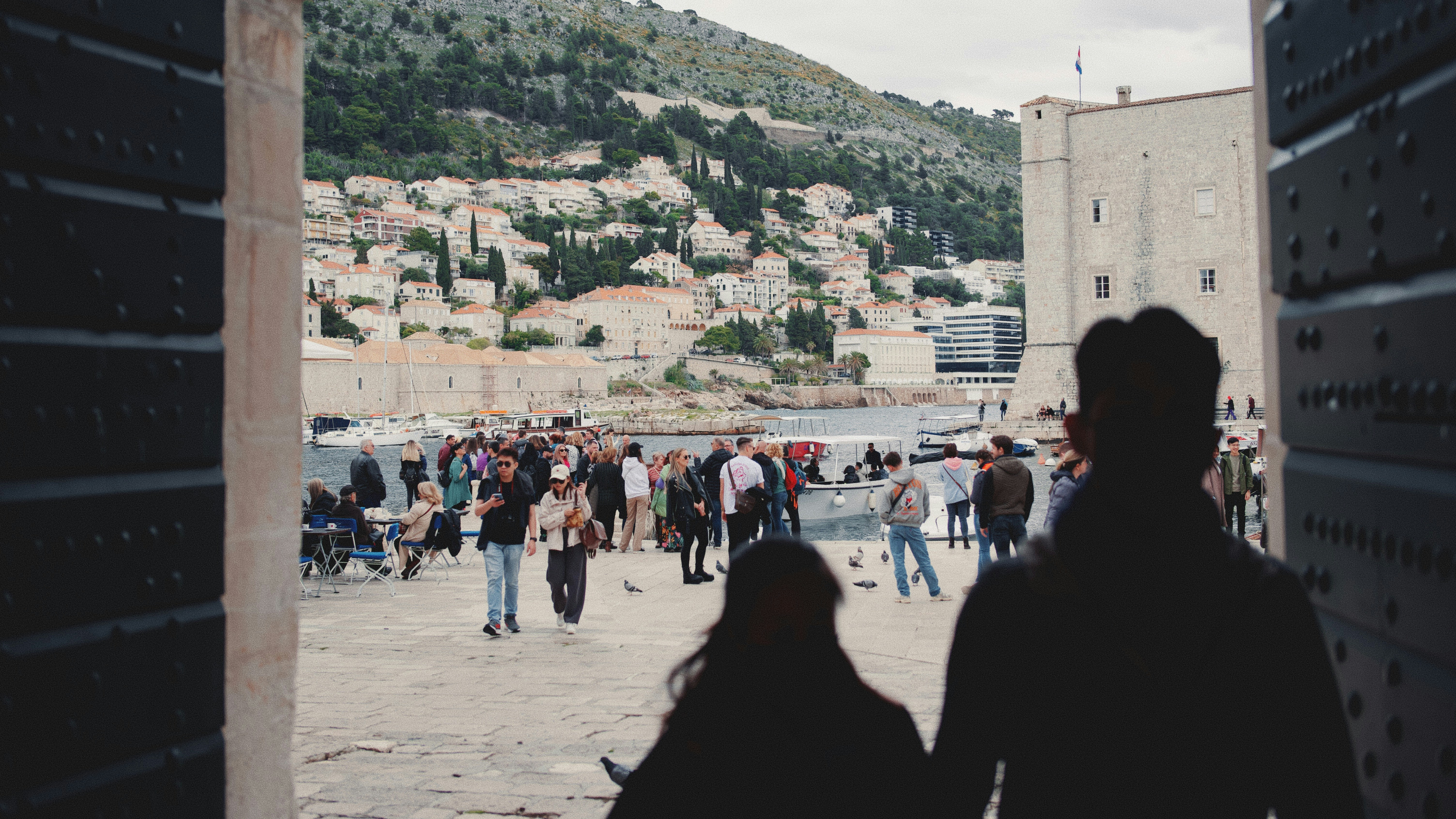 A group of people walking down a street next to a hillside