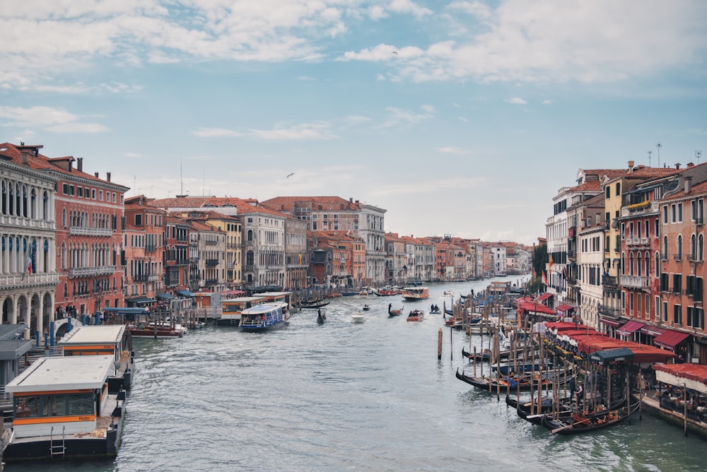 a river filled with lots of boats next to tall buildings