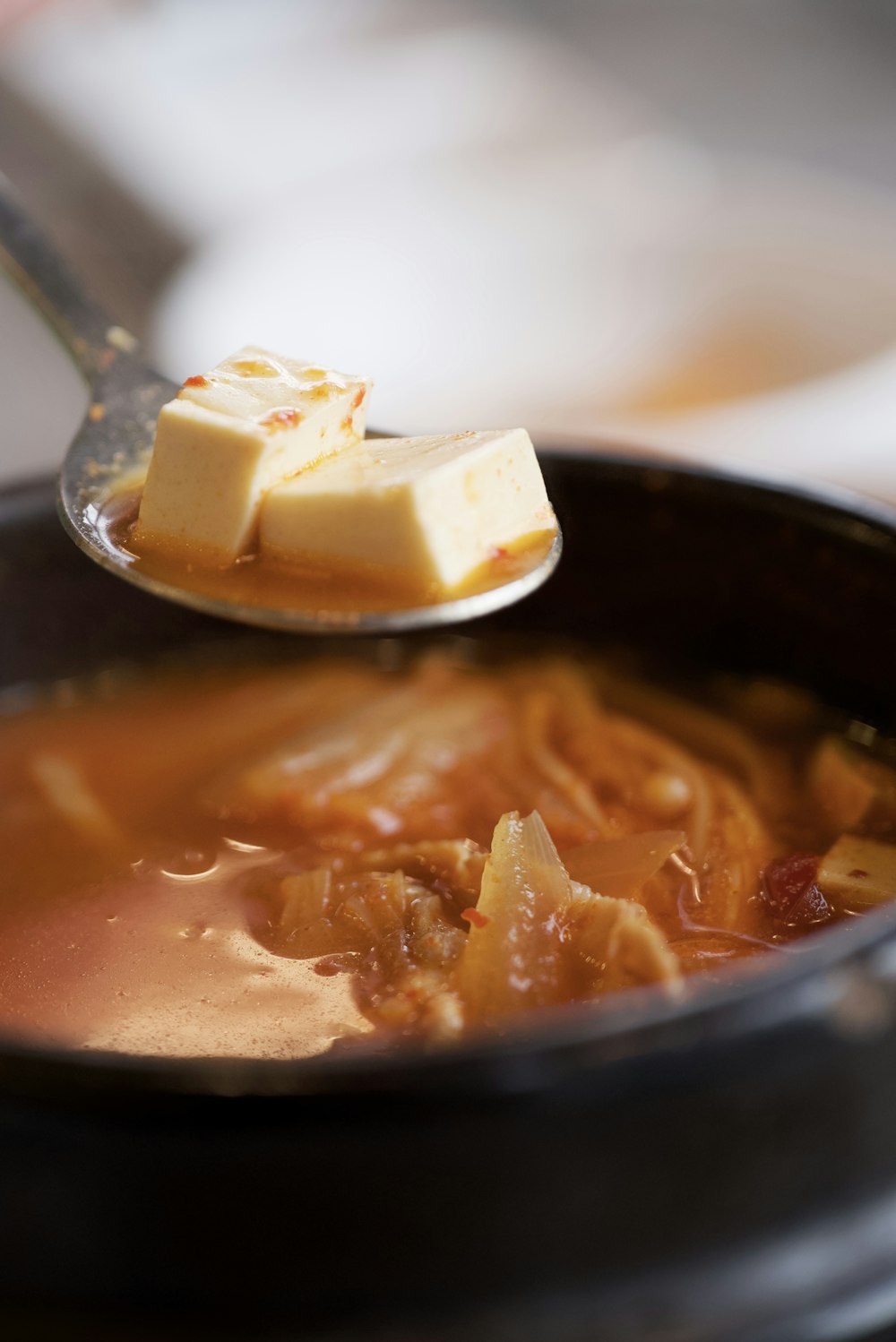 a spoon full of soup with a piece of butter on top of it