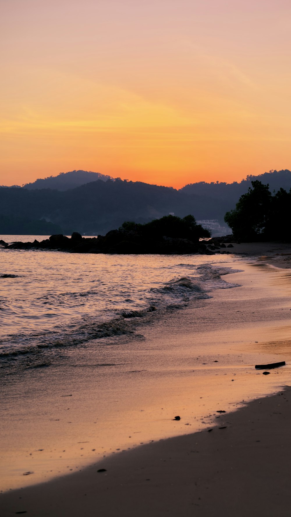 the sun is setting over the water at the beach