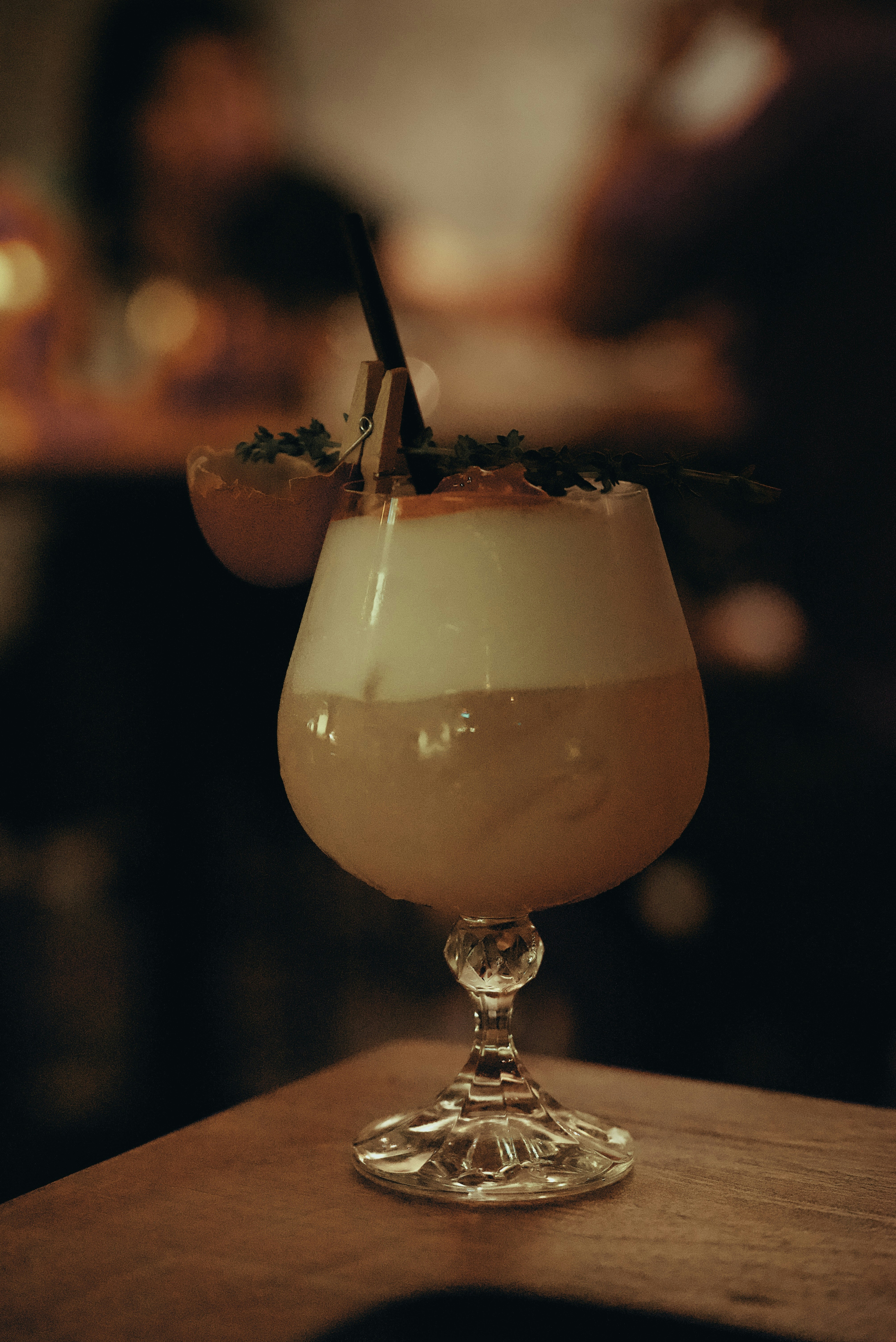 Frothy pisco sour cocktail in glass with lime garnish, warm amber background