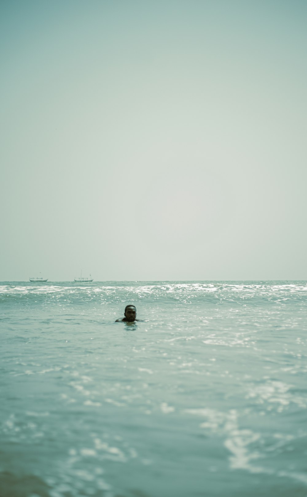 a person swimming in the ocean with a boat in the background