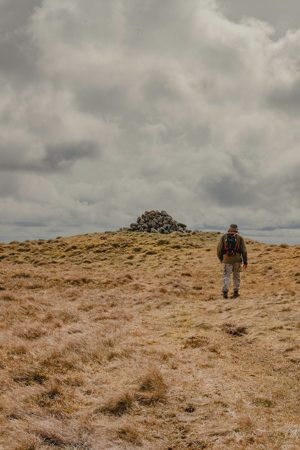 a man walking across a dry grass covered field