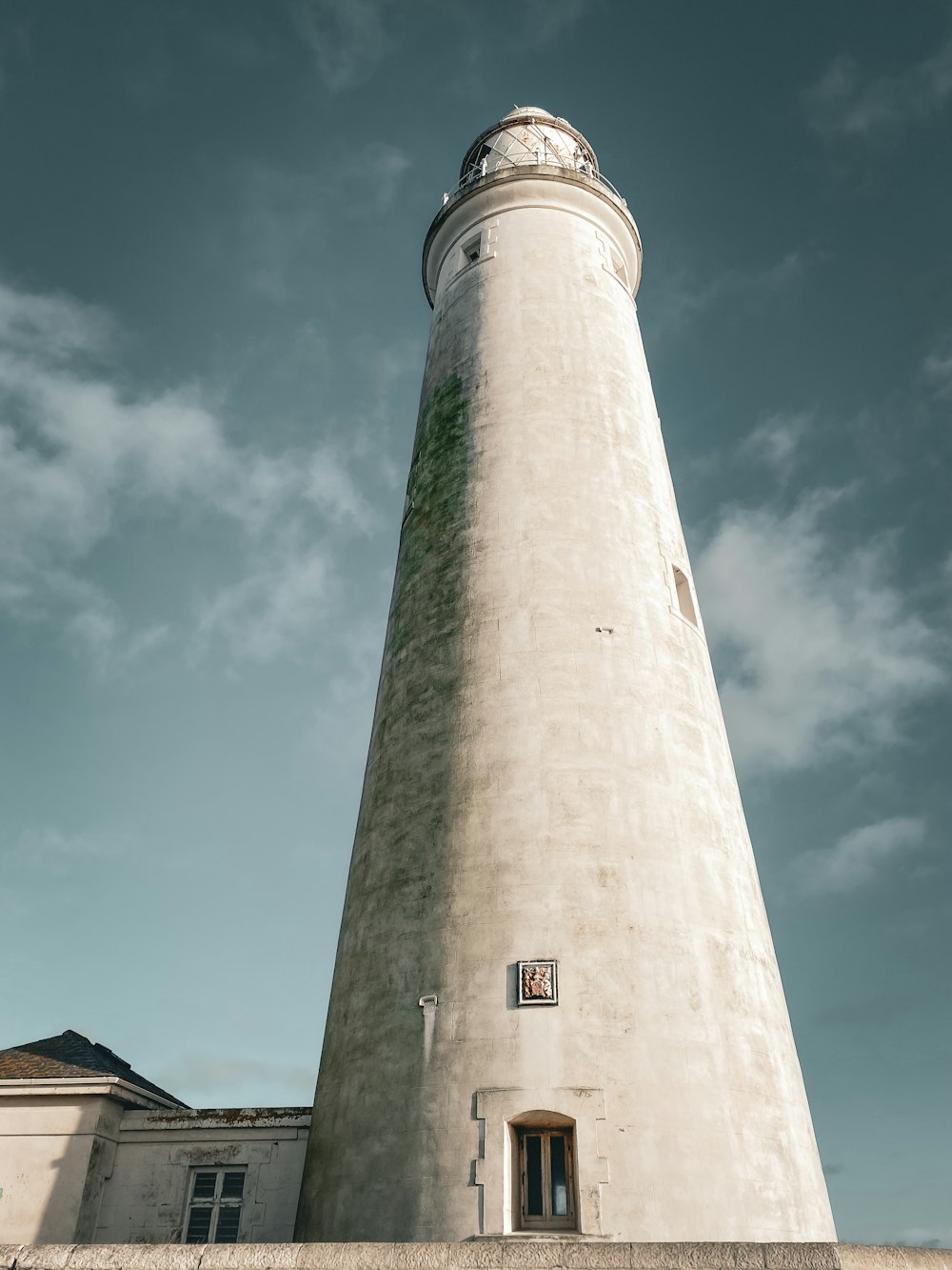 a tall white lighthouse sitting on top of a cement wall