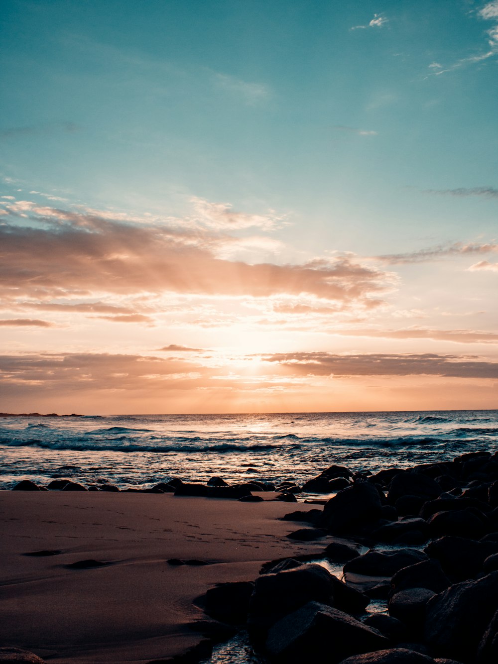 the sun is setting over the ocean on the beach