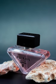 a bottle of prada next to some rocks
