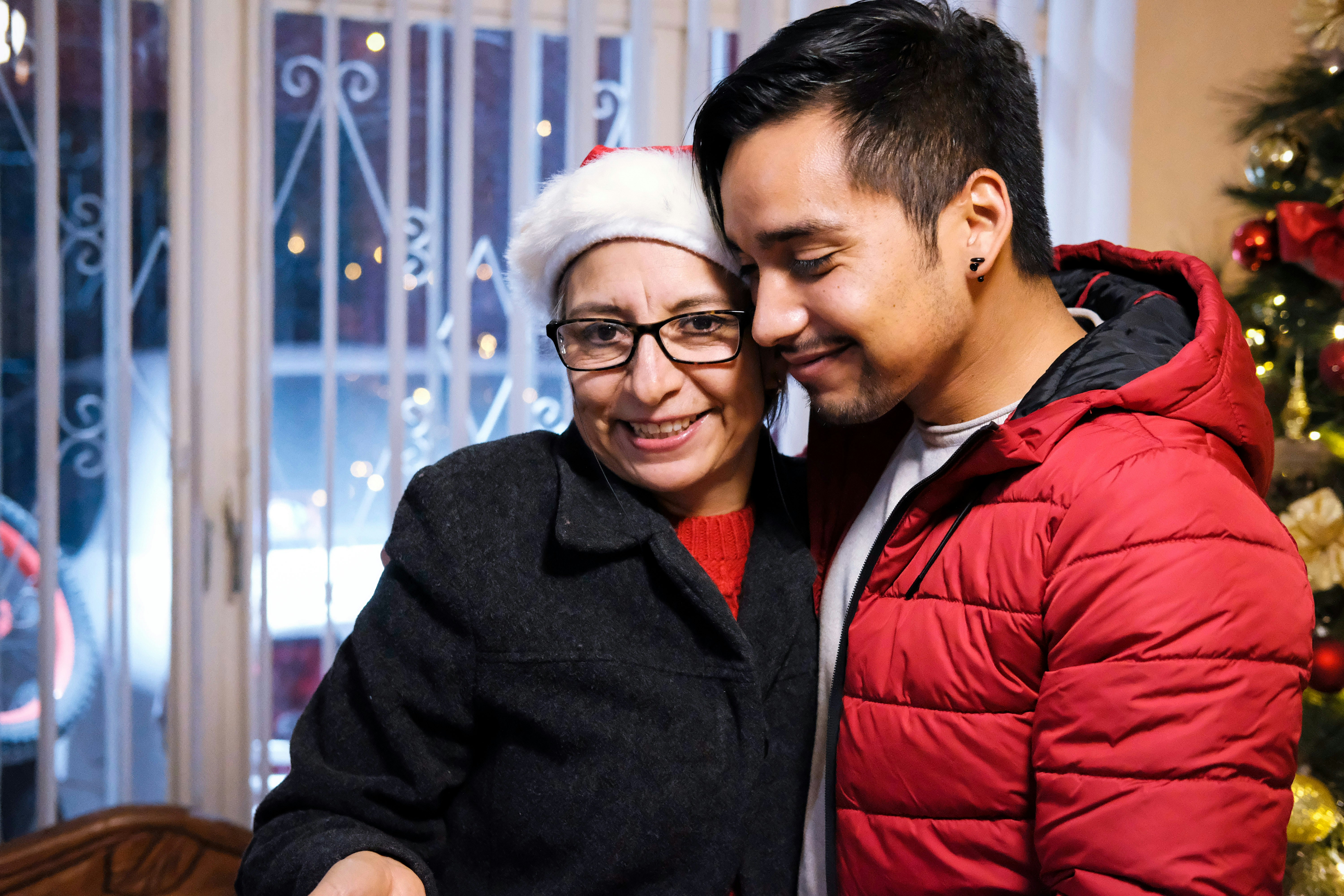 a man and woman standing next to a christmas tree