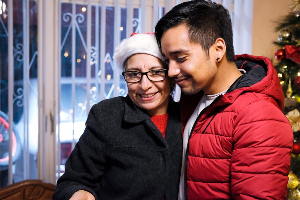 a man and woman standing next to a christmas tree