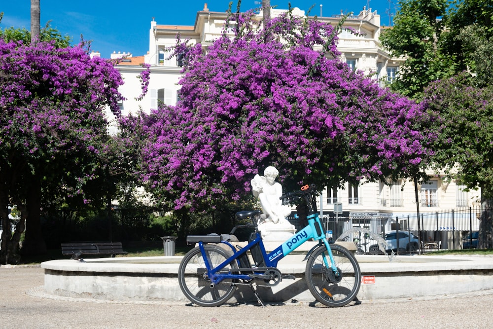 una bicicleta azul estacionada frente a un árbol morado
