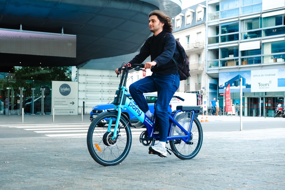 Un hombre montando una bicicleta azul por una calle