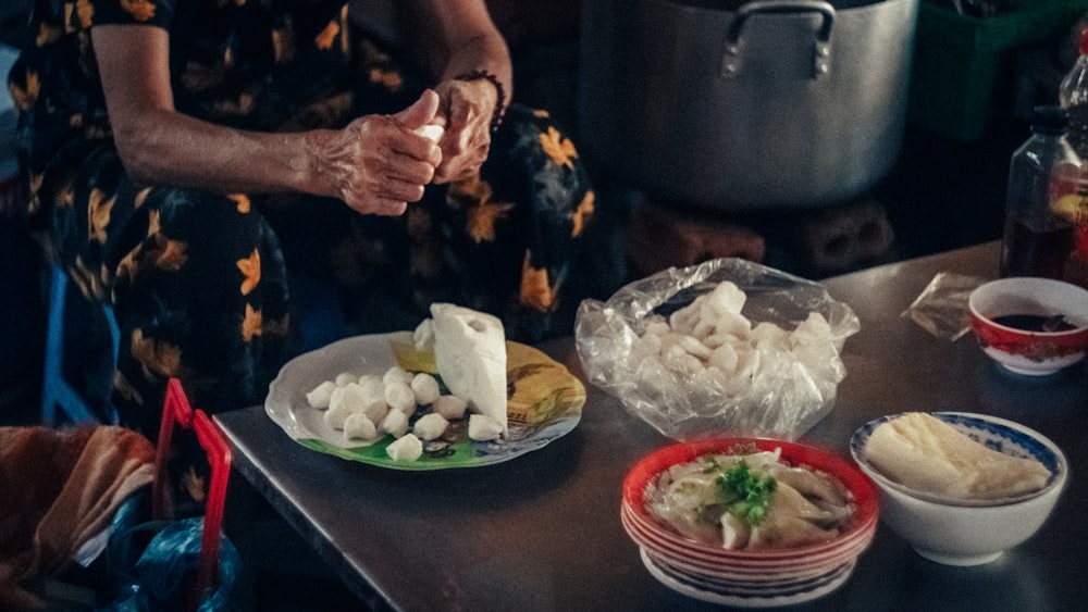 a woman standing over a table filled with plates of food