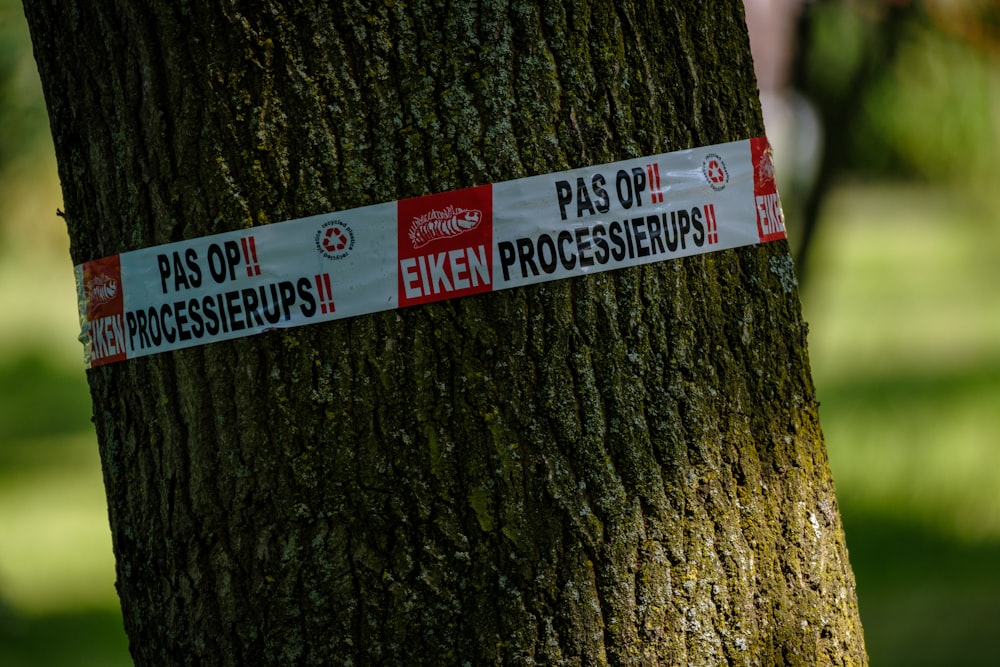a red and white sign on a tree in a park