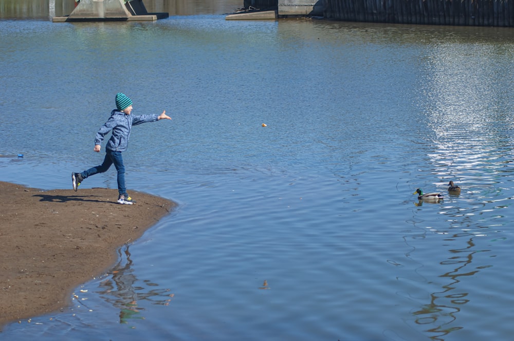 a person standing in a body of water near ducks