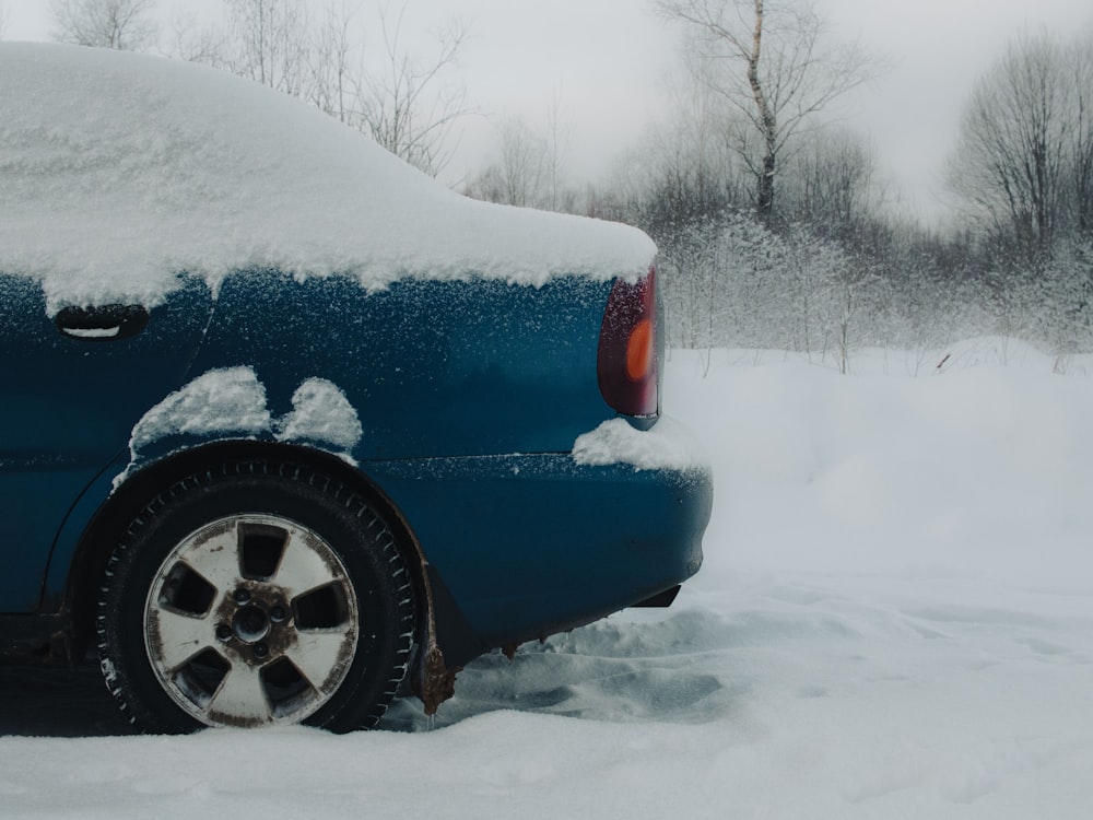 a blue car covered in snow on a snowy day