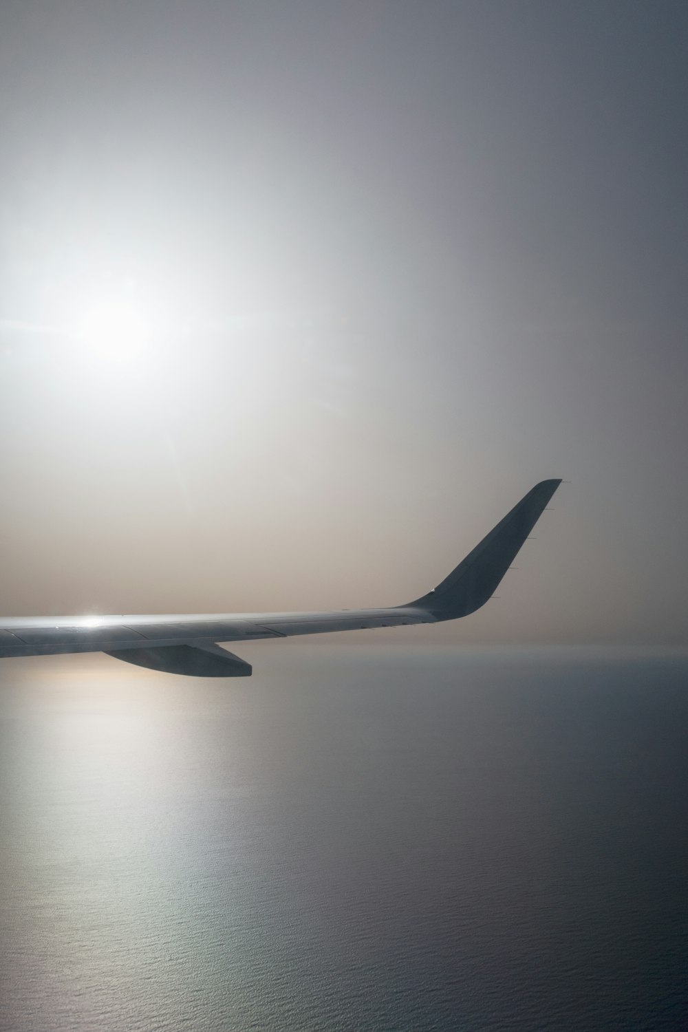 the wing of an airplane flying over the ocean